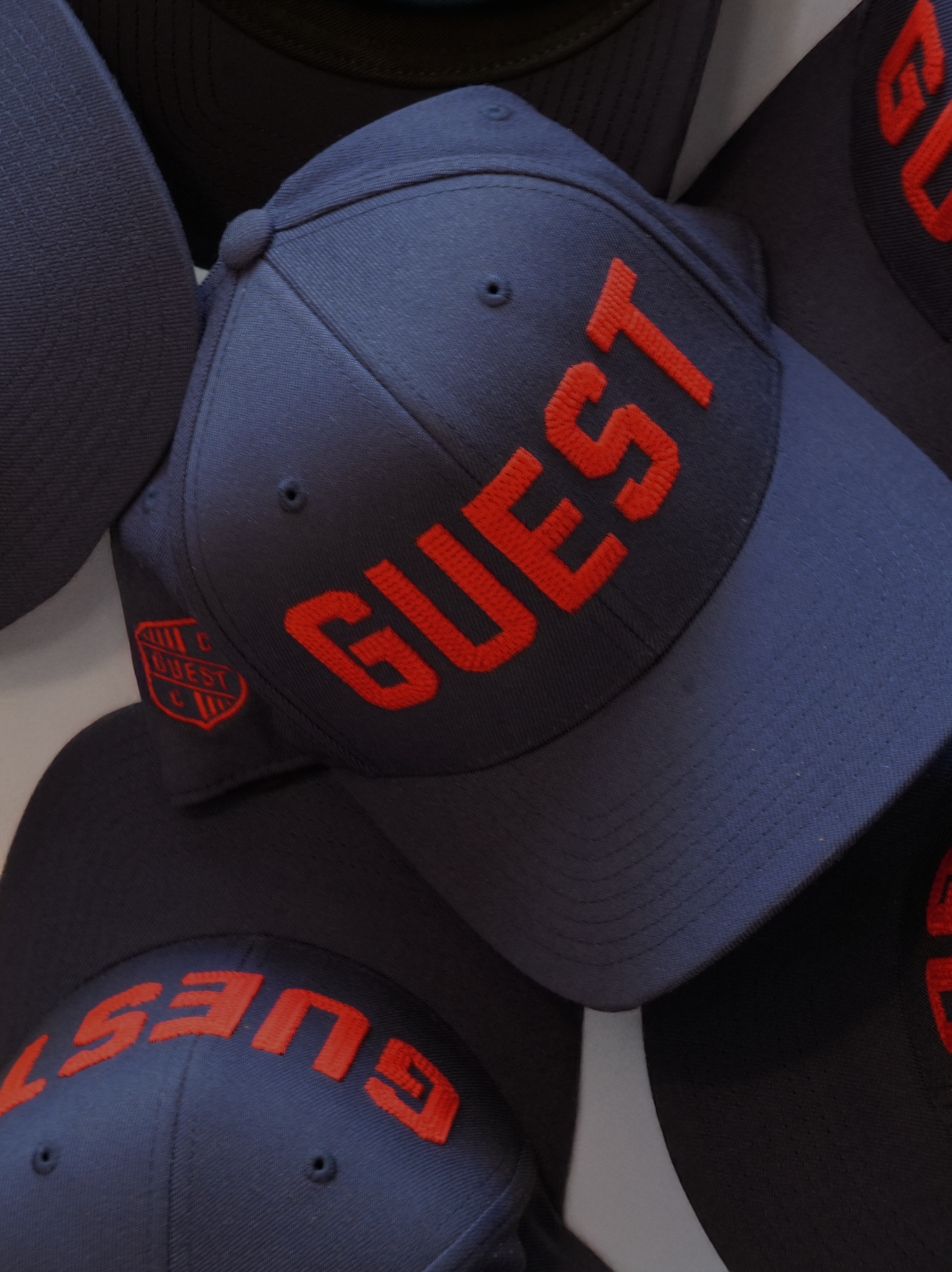 Close-up of a navy Country Club Guest hat with bold red embroidered lettering and Guest crest