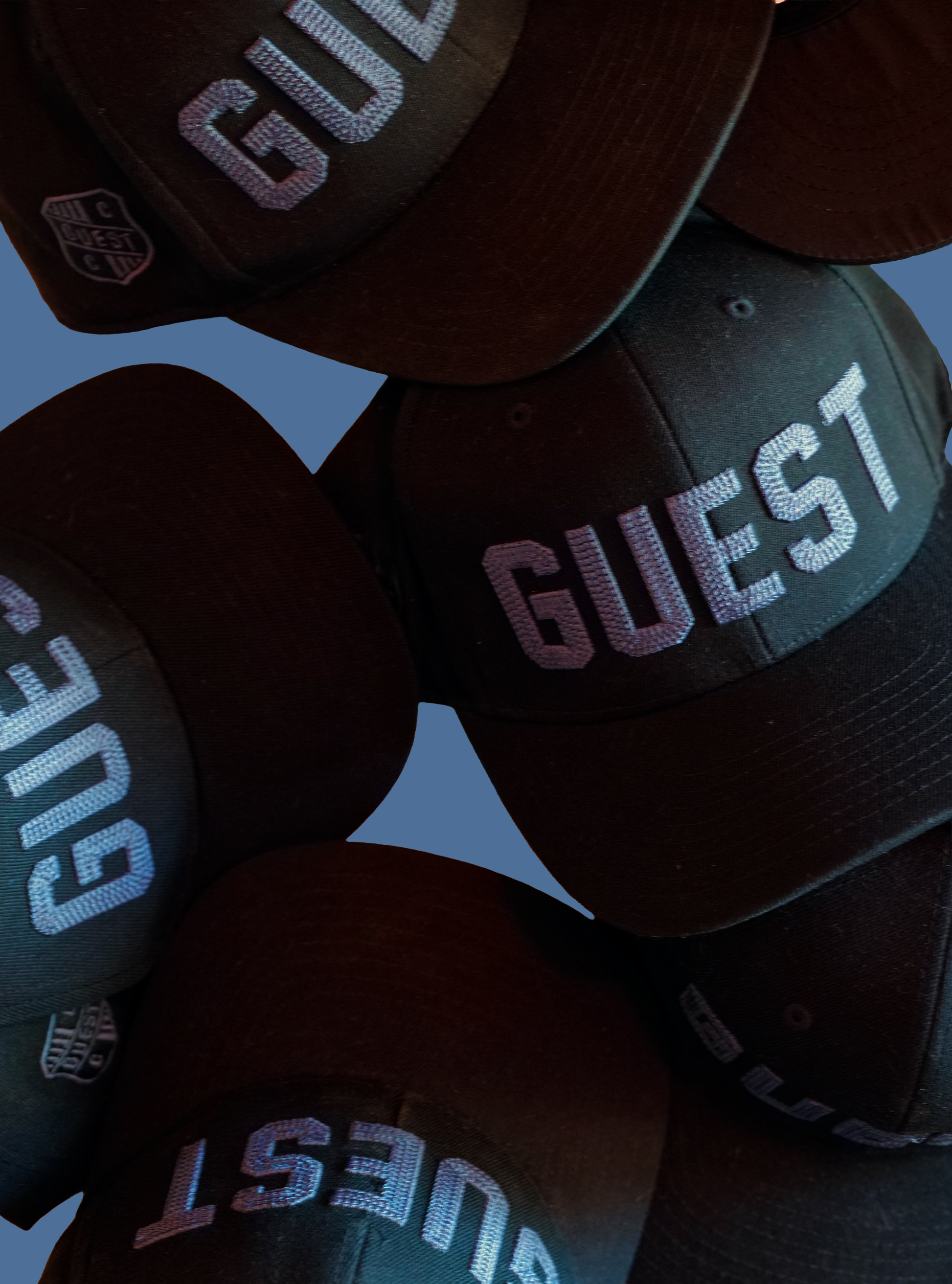 Close-up photo of twilight Country Club GUEST hats with blue embroidered lettering